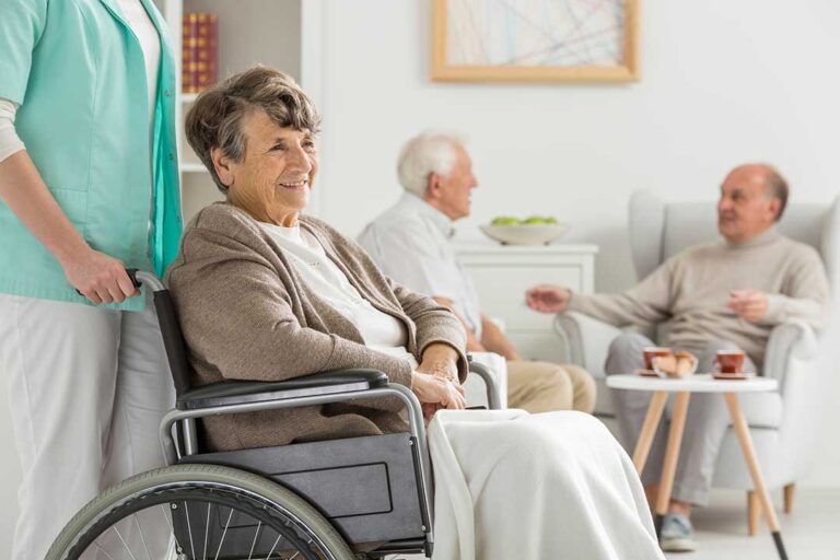 A group of seniors with walkers and a wheelchair boarding a small accessible bus with staff assistance.