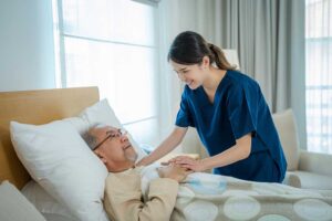 Family members visit an older adult in a bright assisted living lounge with a sign-in desk nearby.