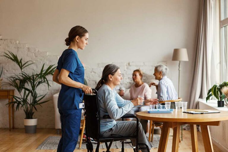 Senior couple sitting together in an assisted living apartment while a caregiver reviews separate care plans.